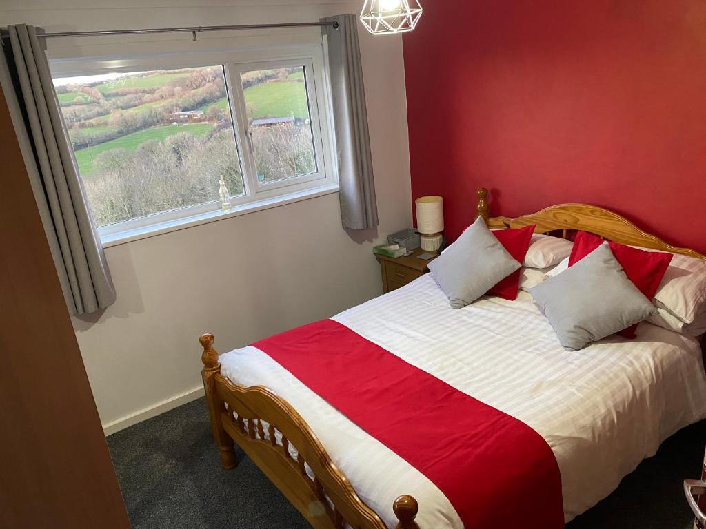 普里茅斯Southway Double Room near Derriford的一间卧室设有一张红色墙壁和窗户的床