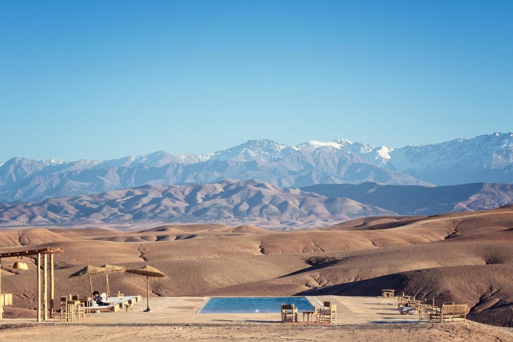 El KariaAlkamar Camp Agafay的沙漠中的游泳池,以群山为背景