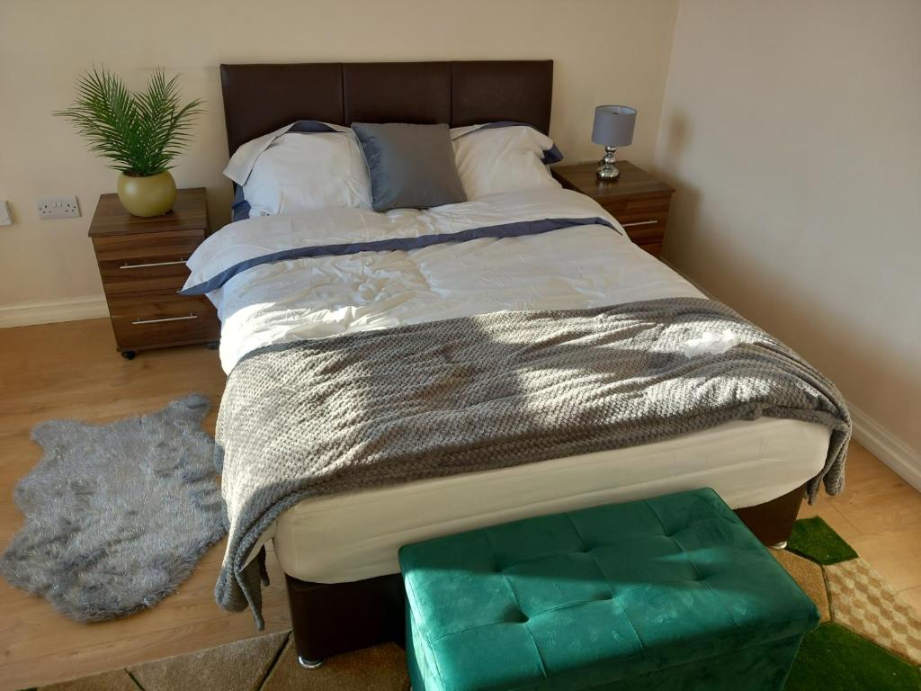ThamesmeadLovely Shared 3 Bed Home Near The Thames的一间卧室配有一张大床和绿色的搁脚凳