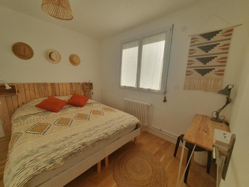 勒芒Maison Zen proche circuit的一间卧室配有一张床、一张桌子和一个窗户。