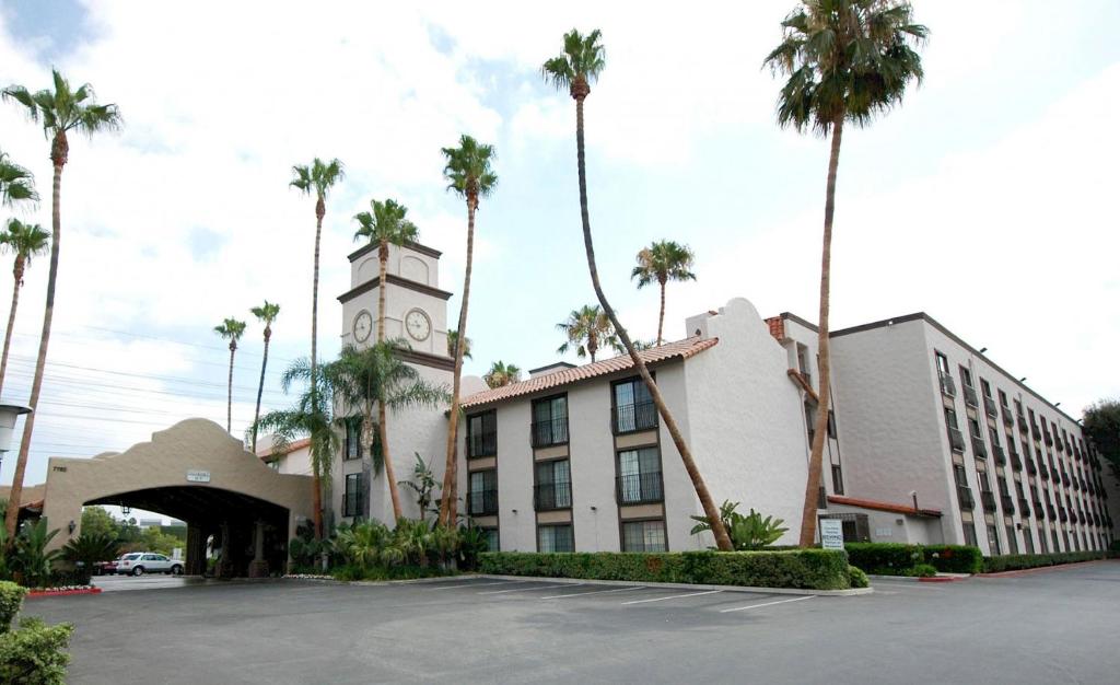 博伟公园Buena Park Grand Hotel & Suites的一座拥有钟楼和棕榈树的建筑