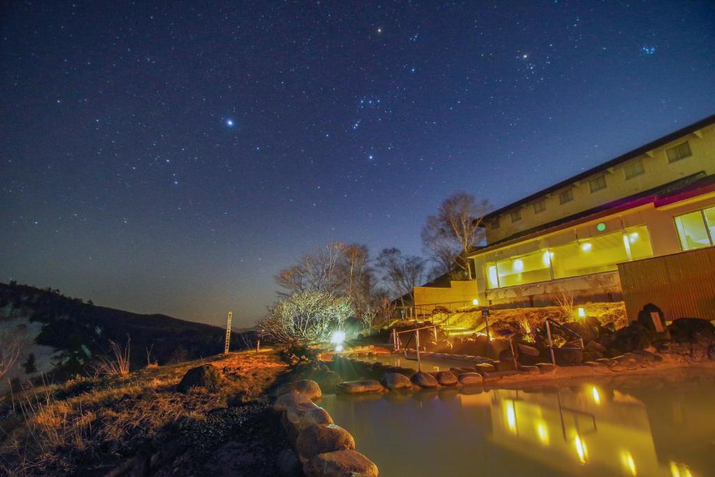 嬬恋村万座王子酒店的一座建筑物,在晚上有一条河在前面