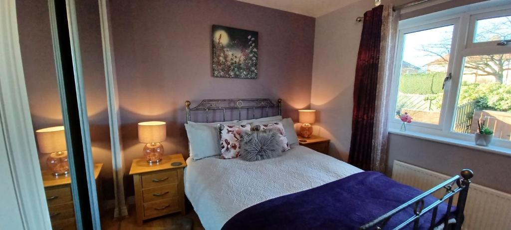 里彭Cosy Retreat - house with double bedroom的一间卧室配有一张床、两盏灯和一个窗户。