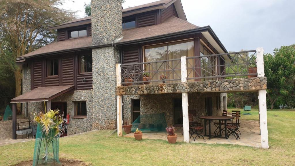 奈瓦沙Kwezi Cottage at The Great Rift Valley Lodge & Golf Resort Naivasha的一座带甲板和烟 ⁇ 的大房子