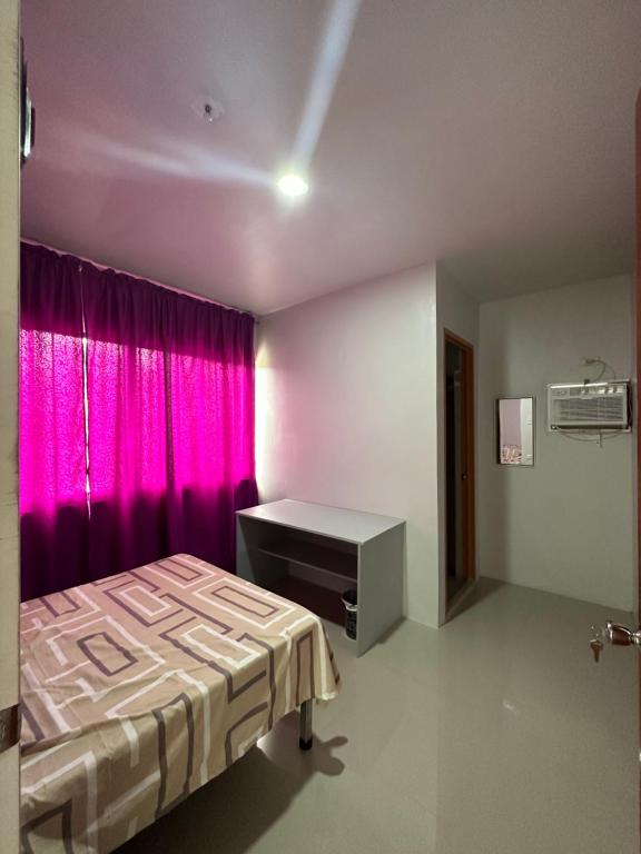 RedDoorz at FJ Hotel Tubungan Iloilo的一间卧室配有一张床和粉红色窗帘