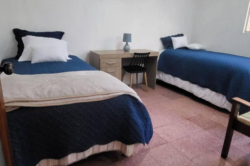 克萨尔特南戈Casa para viajes de descanso o de negocios的一间卧室配有两张床、一张桌子和一把椅子