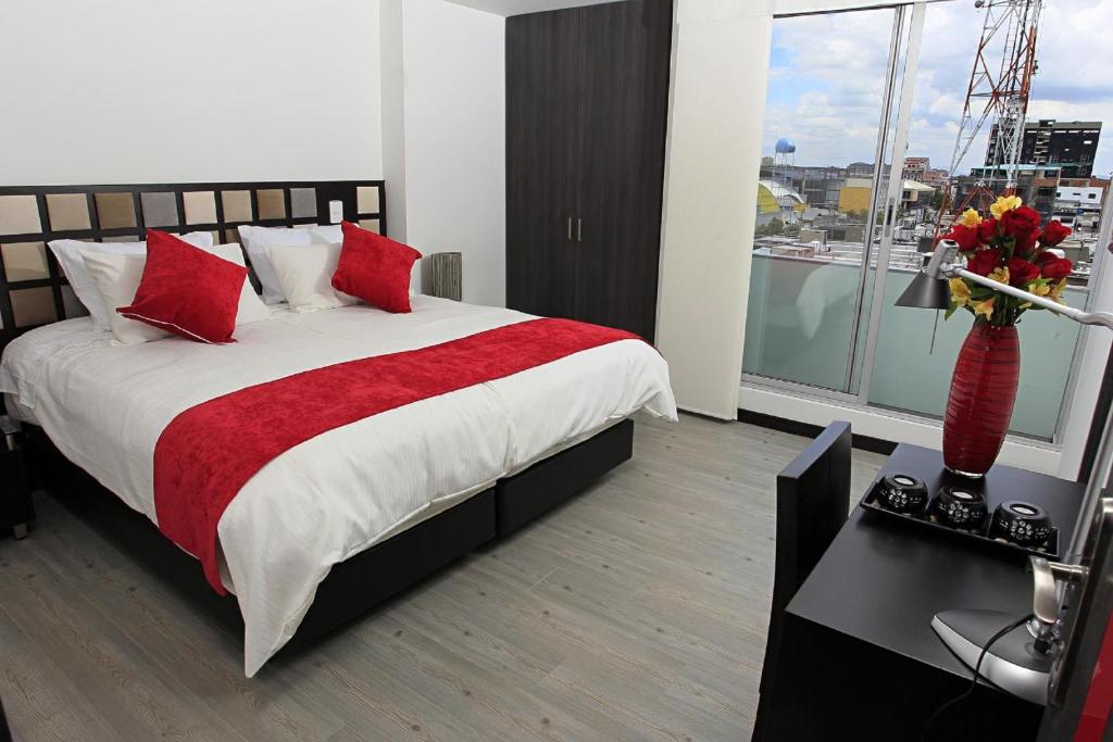 波哥大AW Hotel Ariston的一间卧室配有一张带红色枕头的大床