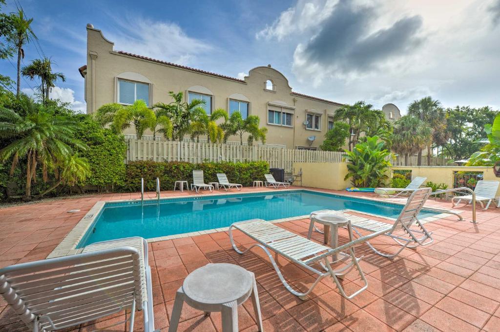 劳德代尔堡Ft Lauderdale Area Condo - Walk to Beach and Shops!的一个带椅子的游泳池以及一座房子