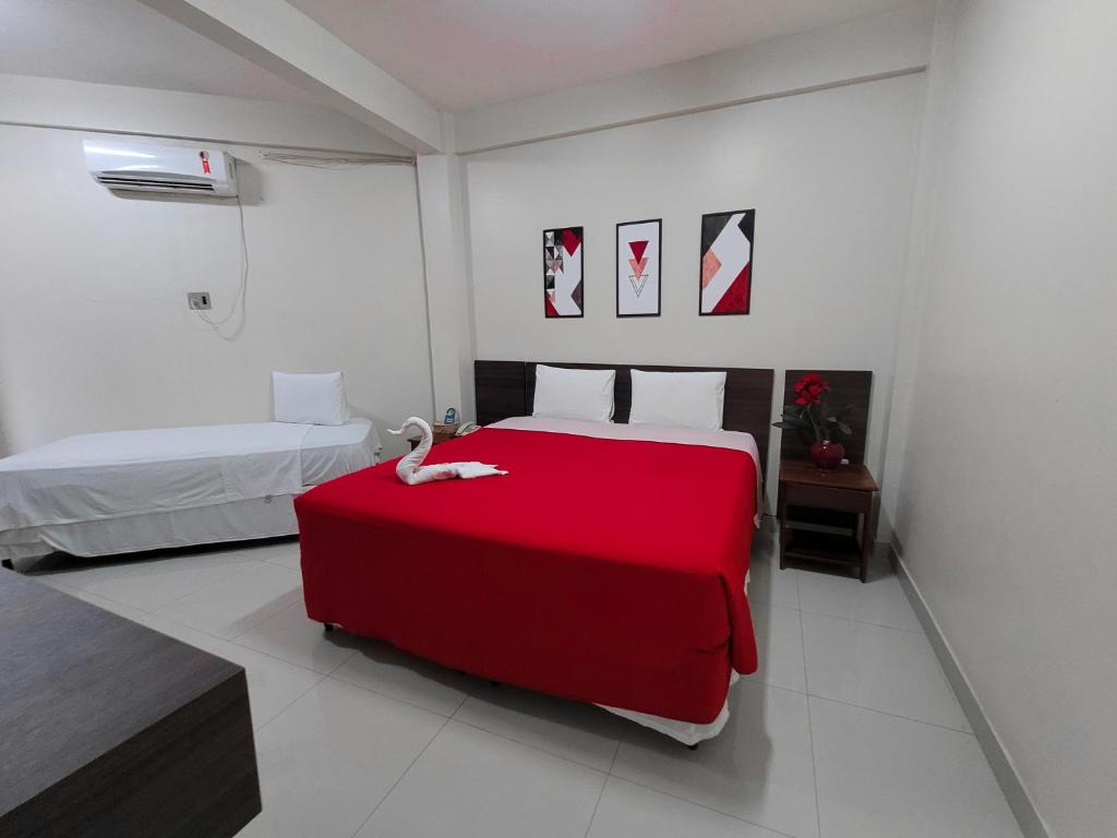 帕劳阿佩巴斯Carajas Hotel的一间卧室配有一张红色的床,上面有天鹅