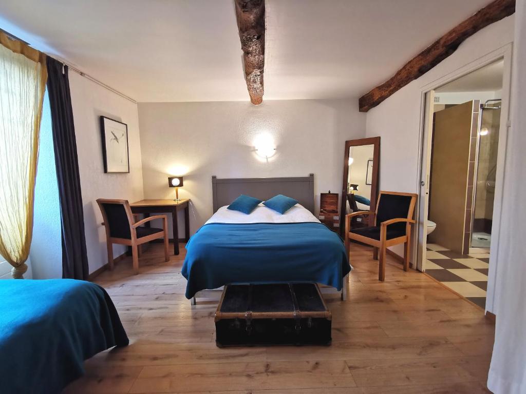 圣皮埃尔德日瓦Logis Hotel Restaurant LA BARGUILLERE的一间卧室配有蓝色的床和桌椅