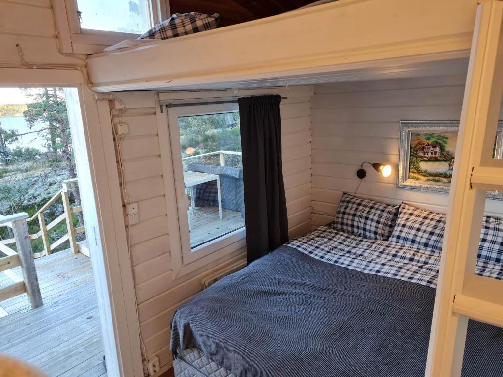 TyresöArchipelago villa, cabin & sauna jacuzzi with sea view, 30 minutes from Stockholm的一个小房子里的一个床位,有门廊