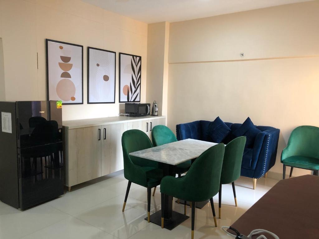 卡拉奇Hamsun Apart Hotel Clifton的一间带桌子和绿色椅子的用餐室