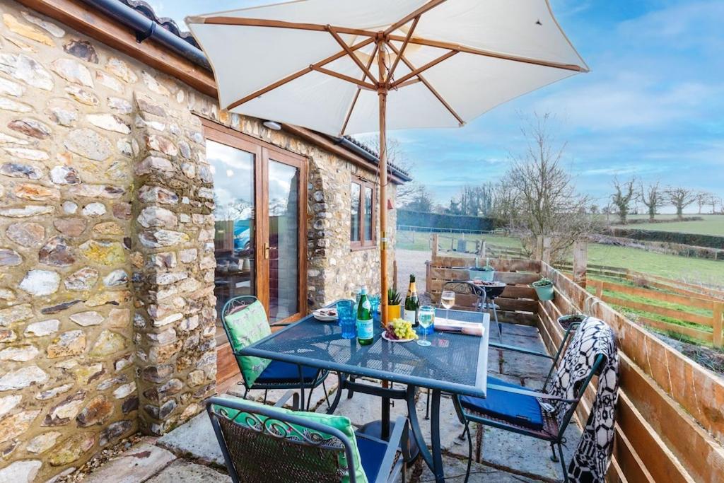 汤顿The Croft @ Warrens Farm的庭院内桌椅和遮阳伞