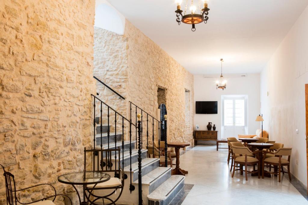 麦地那西多尼亚Hotel Tugasa Casa Palacio Medina Sidonia的客房设有楼梯、桌子和石墙