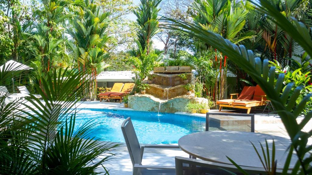 曼努埃尔安东尼奥La Vela Boutique Hotel的一个带桌椅和棕榈树的游泳池