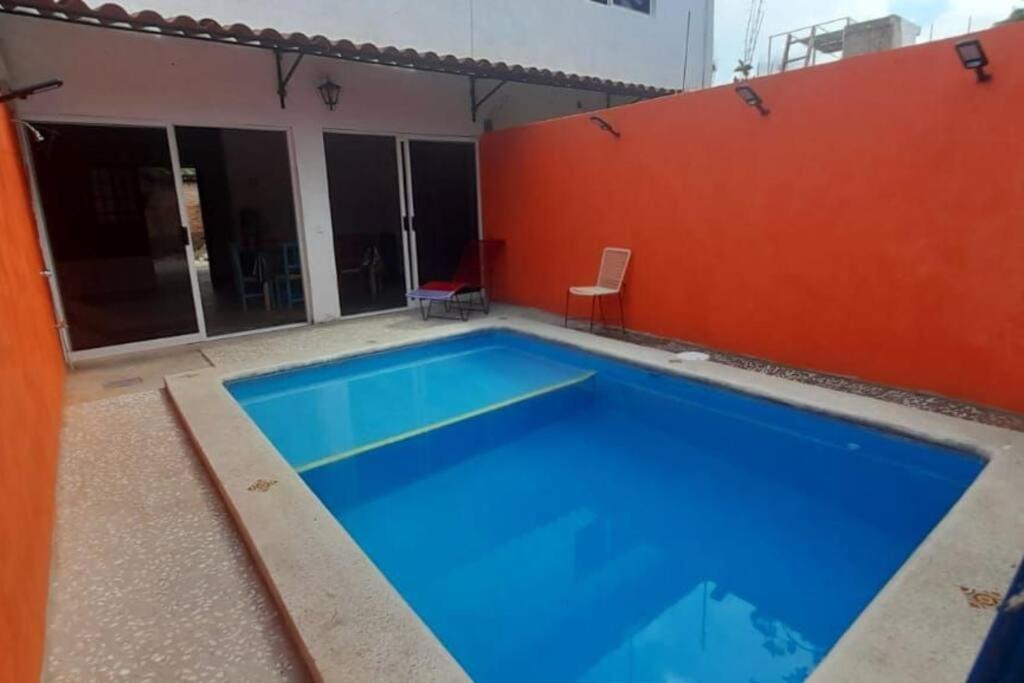 拉佩尼塔德加尔特姆巴C911 Casa 2 niveles y alberca privada的一座大型蓝色游泳池,设有红色的墙壁