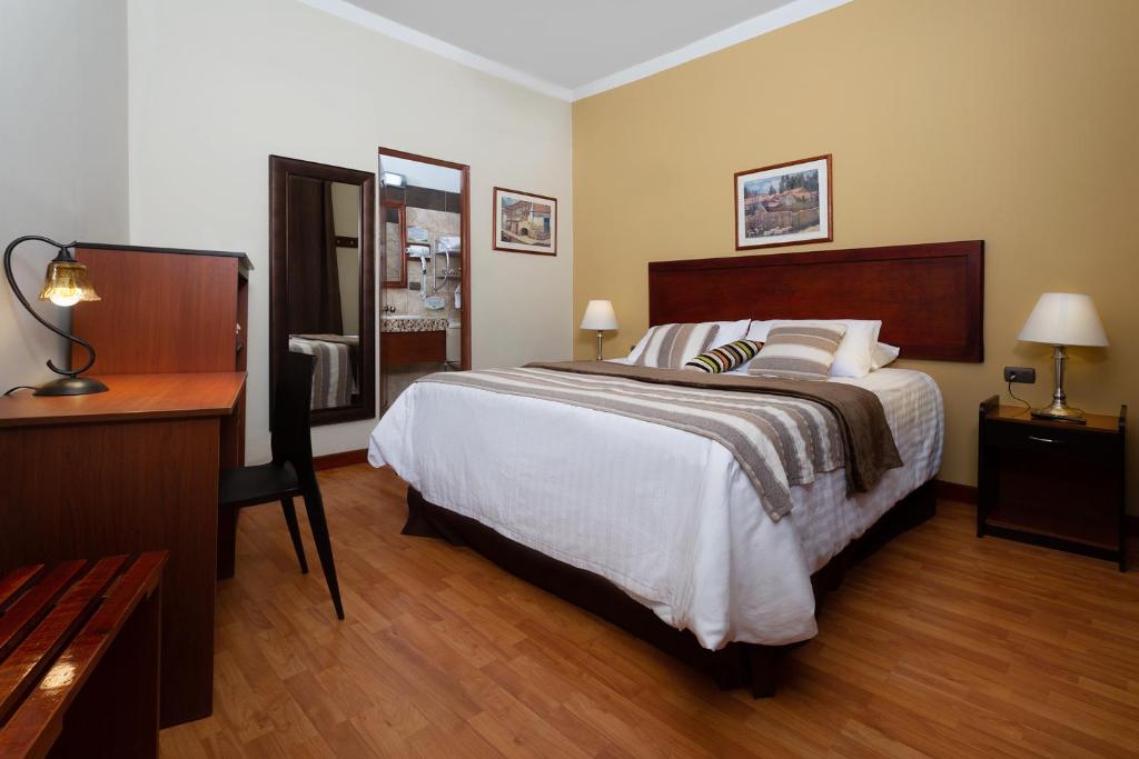 阿雷基帕卡萨代阿维拉住宿加早餐旅馆的一间卧室配有一张大床、一张桌子和一张四柱床。