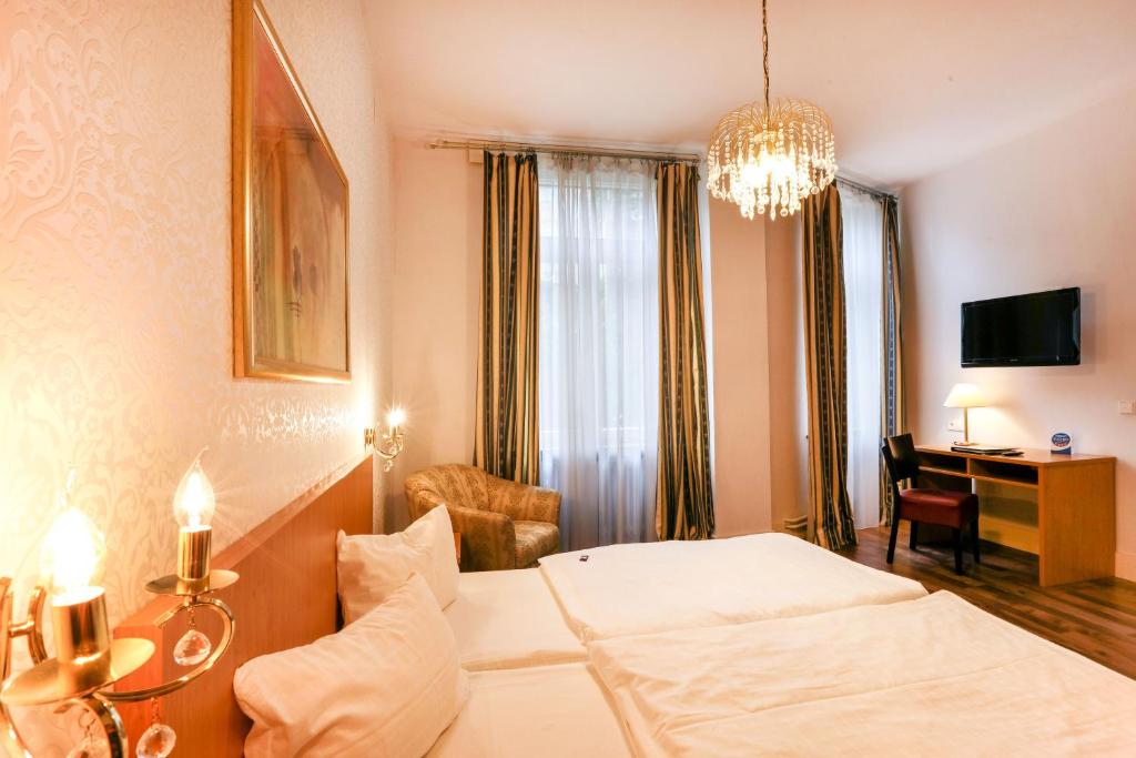 卡尔斯鲁厄马克格拉弗勒酒店的酒店客房配有一张床、一张书桌和一个吊灯。