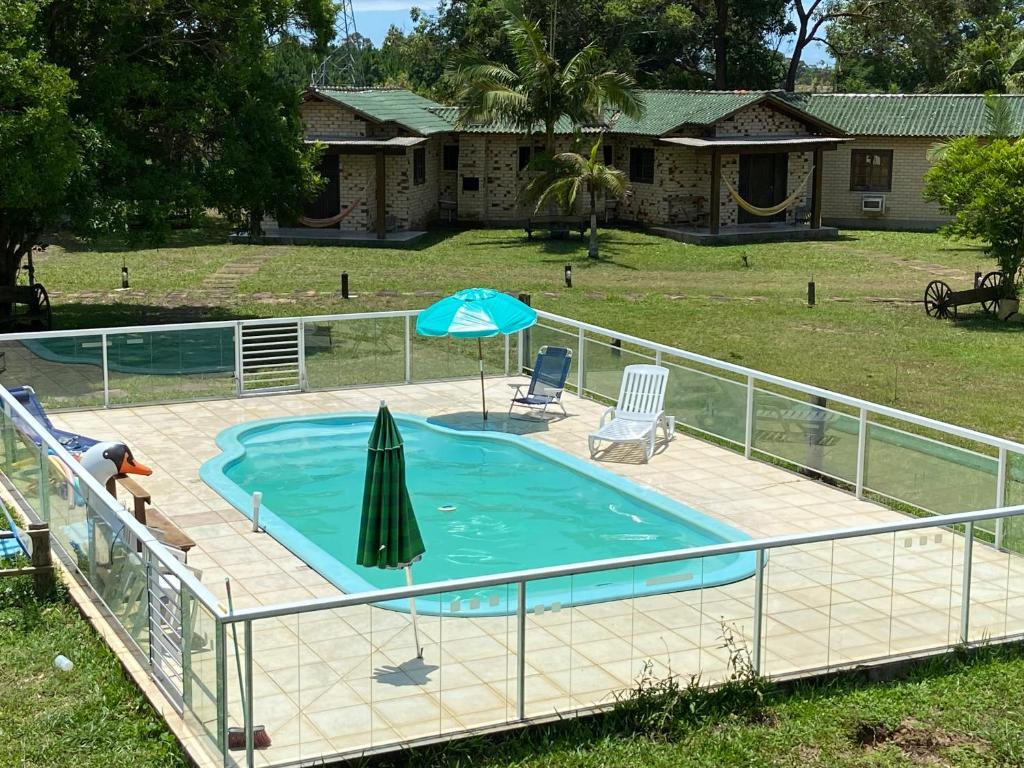 托雷斯Pousada Haras Trevo de Ferro, Praia, Piscina e Campo的一个带遮阳伞和桌椅的游泳池