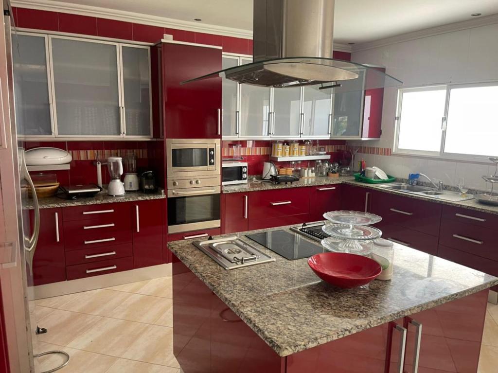 BelasCasa Luxuosa na Ilha do Mussulo的厨房配有红色橱柜和花岗岩台面