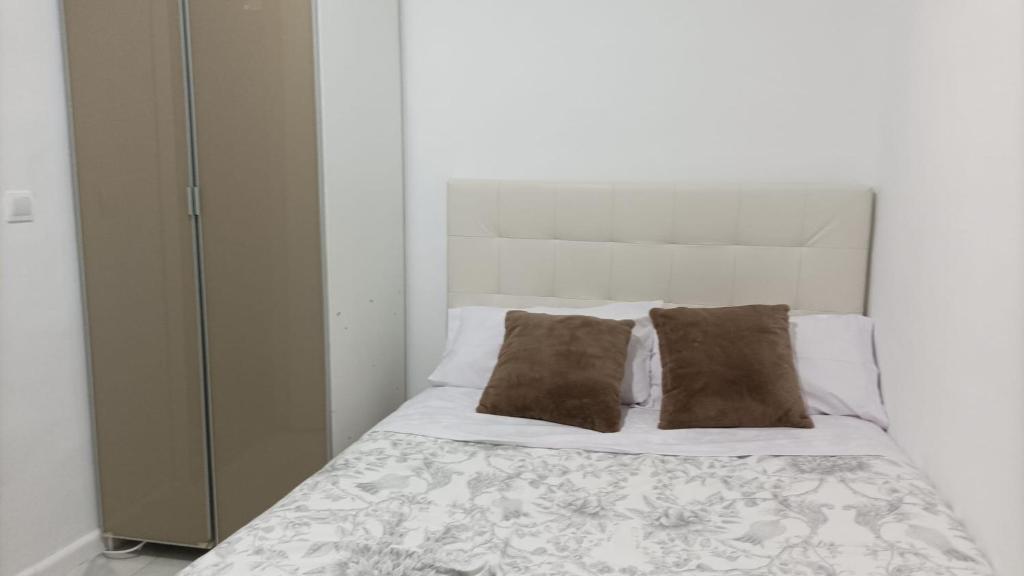 马德里Habitación cerca centro de Madrid的一张带两个枕头的白色床和一个衣柜