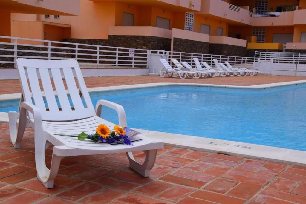 卡巴纳斯·德·塔维拉Apartamento Duja的游泳池旁的白色椅子