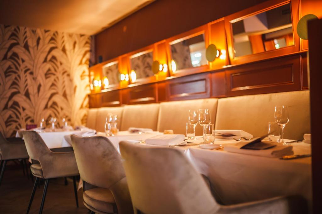 格罗宁根Hotel Halbert的餐厅配有白色的桌椅和灯光