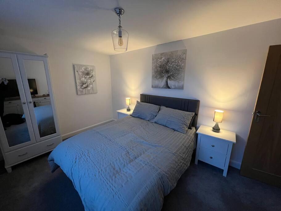 绍斯波特The Hideaway Southport的一间卧室配有一张带2个床头柜和2盏灯的床。