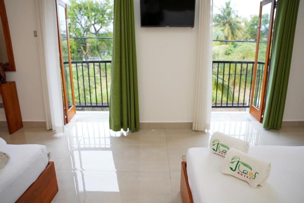 尼甘布J Leaf Hotel By Blue Bird的客房设有两张床、一台电视和一个阳台。