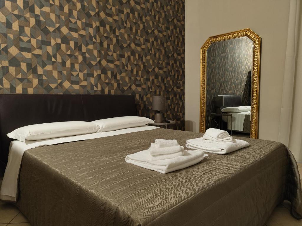 卡塔尼亚特里雅斯特酒店的一间卧室配有一张床、镜子和毛巾