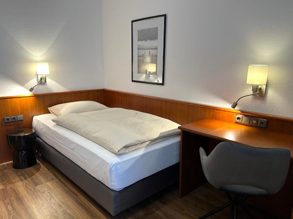 勒沃库森阿尔卡德酒店的一间卧室配有一张床、一张桌子和一把椅子