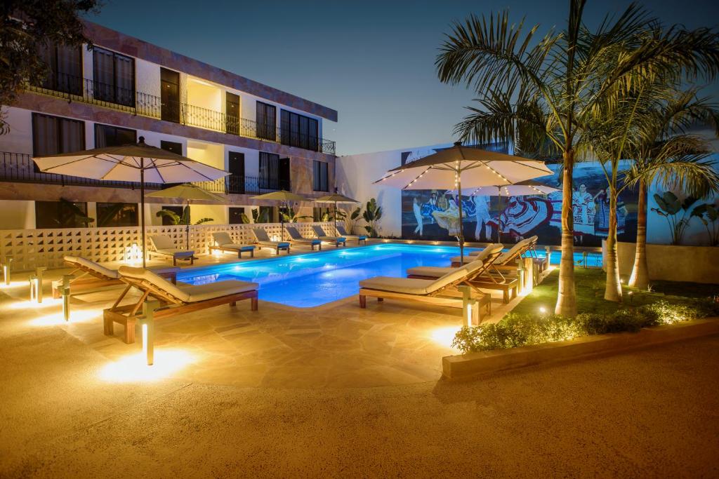 埃斯孔迪多港Hotel Camino Del Sol的一座带椅子和遮阳伞的游泳池位于一座建筑旁边