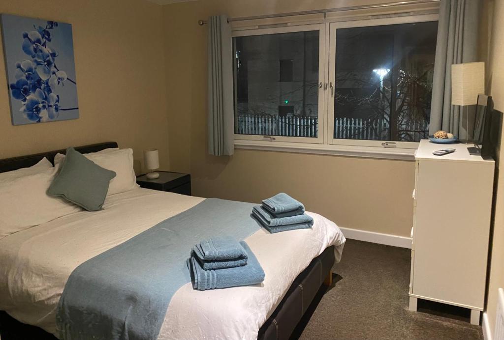 格拉斯哥City Centre 2 bedroom apartment, secure parking.的一间卧室配有一张带折叠毛巾的床。