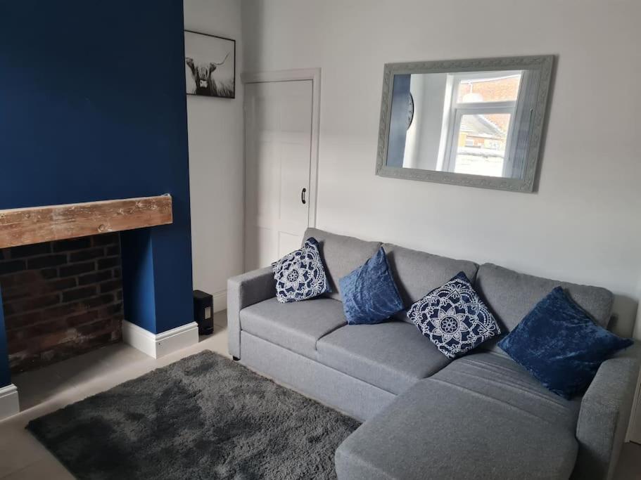 特伦特河畔斯托克Primrose Stays - 3 bedroom House的客厅配有灰色的沙发和蓝色的枕头。