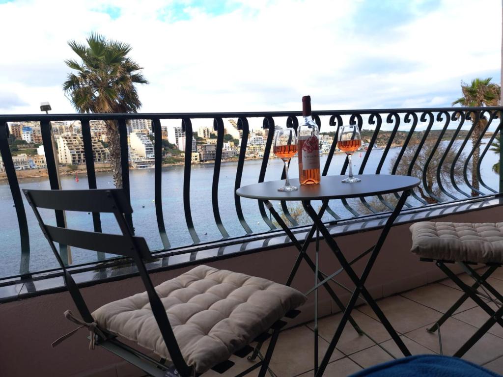 圣保罗湾城Seafront Apartment in St. Paul's Bay的阳台配有桌子和两杯葡萄酒