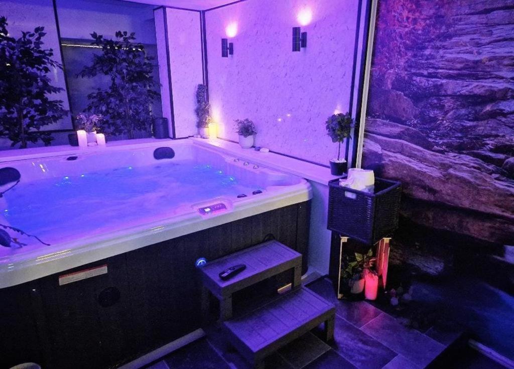 伯明翰Luxury 9ine SUPER BEAUTIFUL JACUZZI APARTMENT WITH BALCONY的浴室配有带紫色照明的大浴缸
