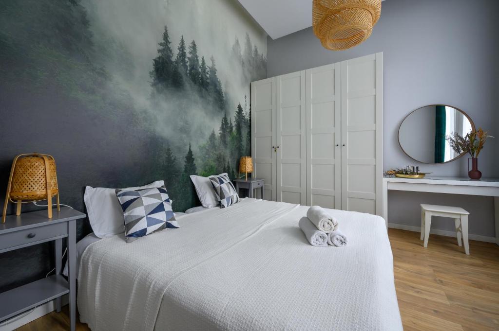 罗兹罗兹市中心租赁公寓的卧室配有一张大床,墙上挂有绘画作品
