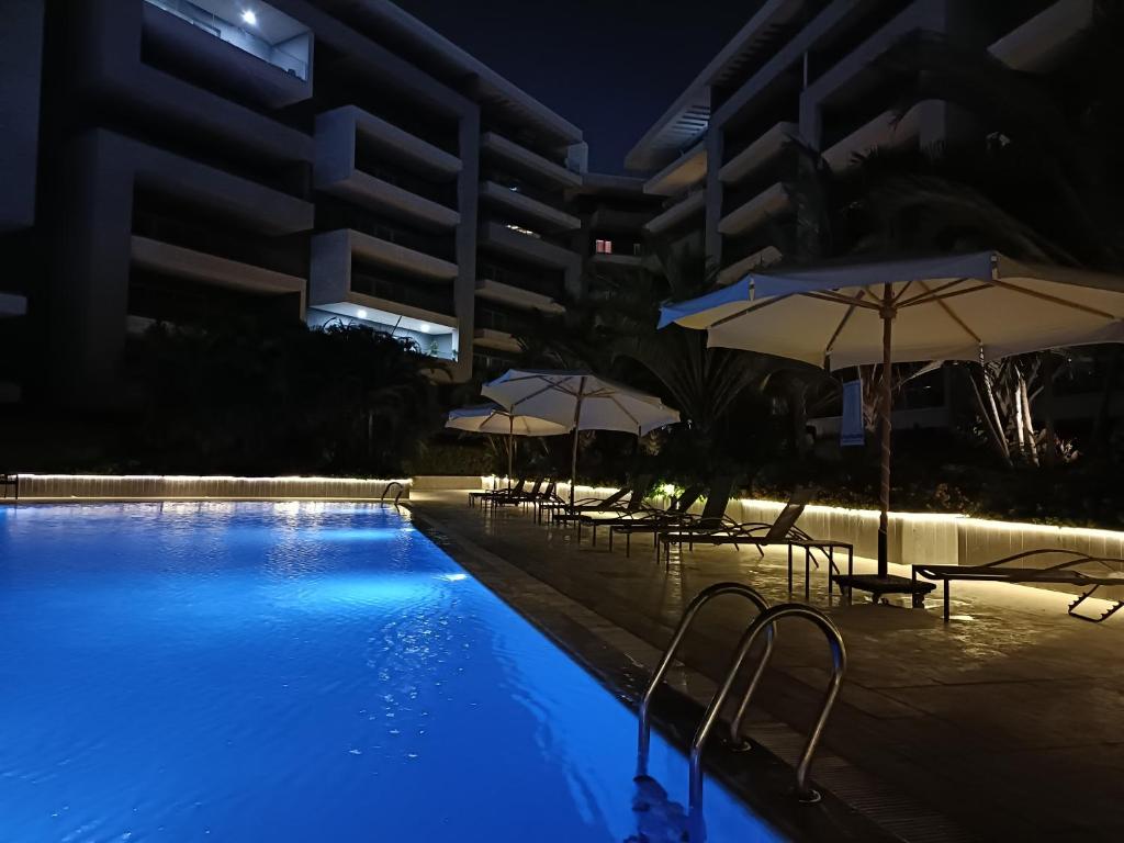 开罗Sheraton ocean 203 - Private apartments的大楼前的游泳池配有椅子和遮阳伞