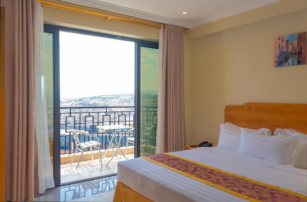 基加利Tropical Plaza Apartments的一间卧室设有一张床和一个阳台的大窗户