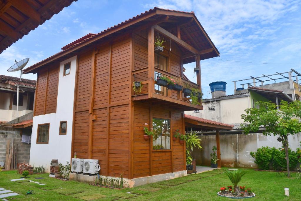 ItapemirimMillicent Residence - Chalet Milly e Chalet Iris - Itaoca Praia - ES的带阳台的木屋(位于庭院内)