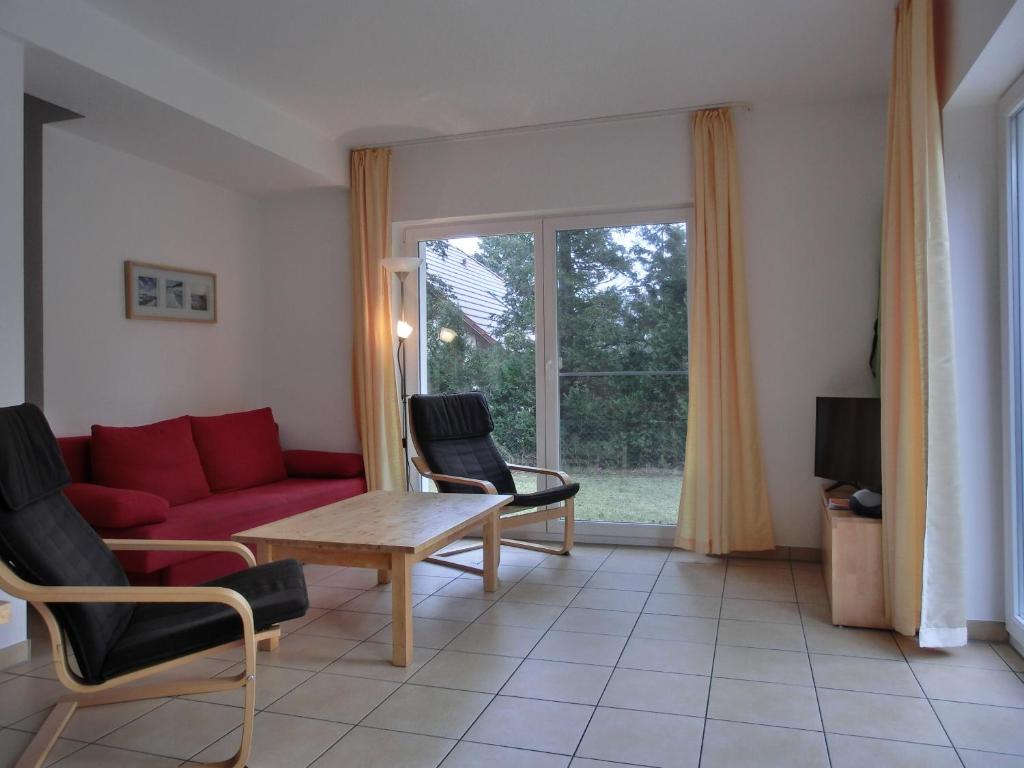 HirschburgFerienwohnung NH10的客厅配有红色的沙发、椅子和窗户