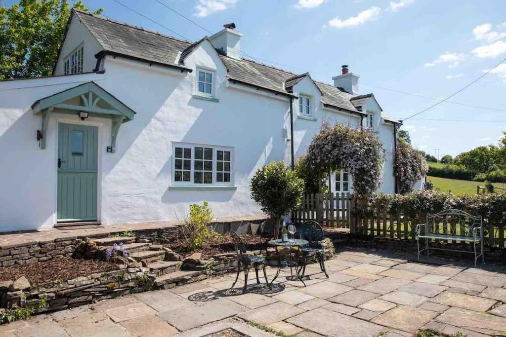 克里克豪厄尔Cosy Country Cottage; Brecon Beacons的白色的房子,设有绿门和庭院