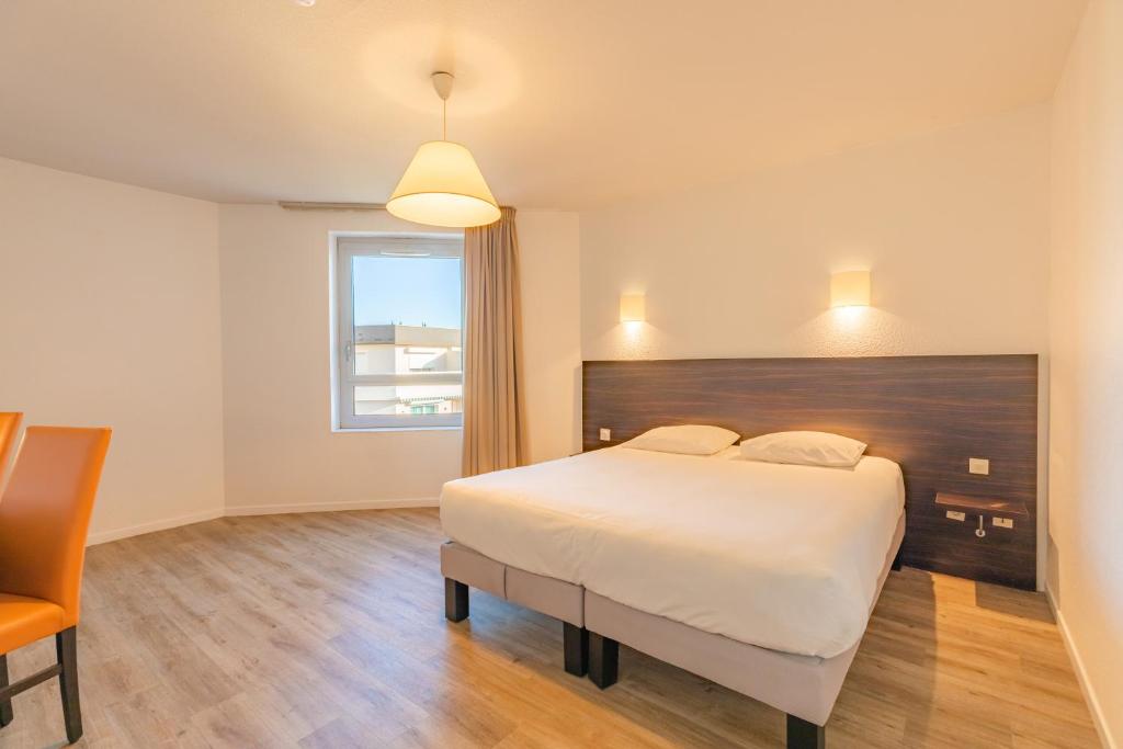 盖拉德Appart'City Classic Genève - Gaillard的卧室配有一张白色大床和一把椅子