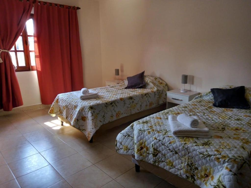 萨尔塔Lo de Chavela的一间卧室设有两张床,窗户配有红色窗帘