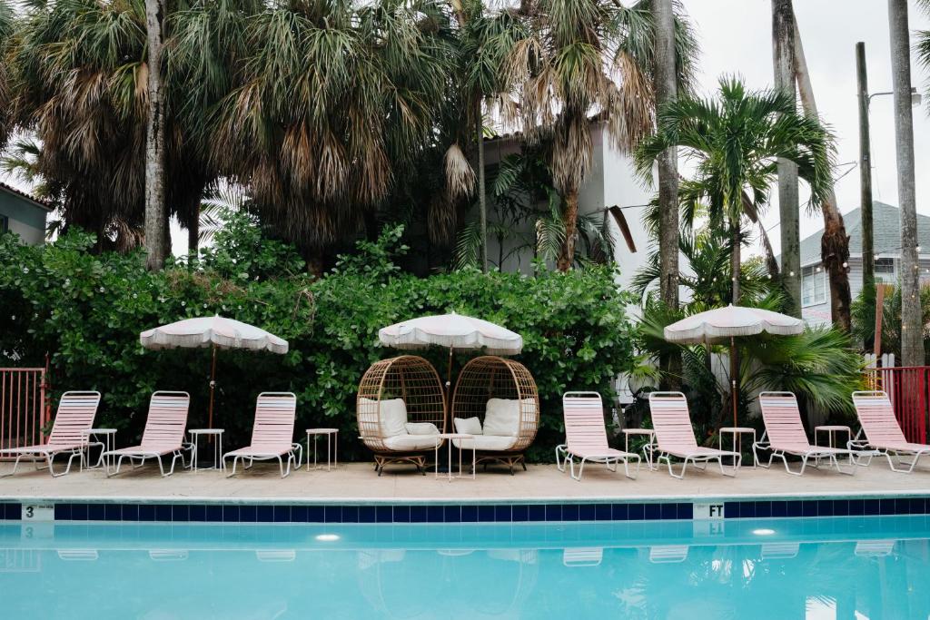 迈阿密Selina Miami River的一组椅子和遮阳伞,位于游泳池旁