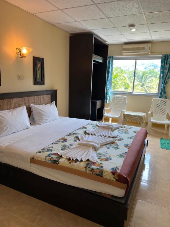 蔻立RT KhaoLak Hotel的一间卧室配有一张大床,另一间卧室配有椅子