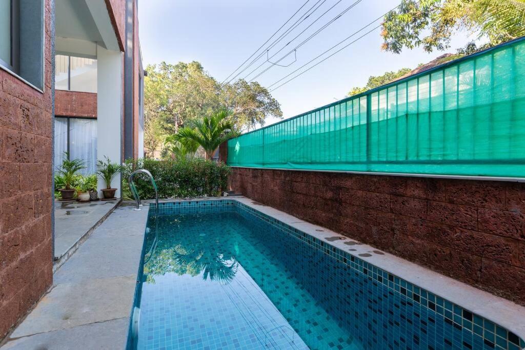 果阿旧城Luxury 3BHK Villa with Private Pool near Anjuna的砖墙旁边的游泳池和大楼
