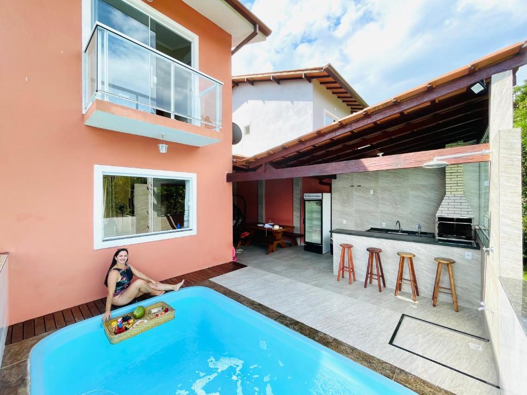 帕拉蒂Casa Premium Paraty com Piscina - Passeio de Escuna de Cortesia incluso的坐在房子前的游泳池上的女人