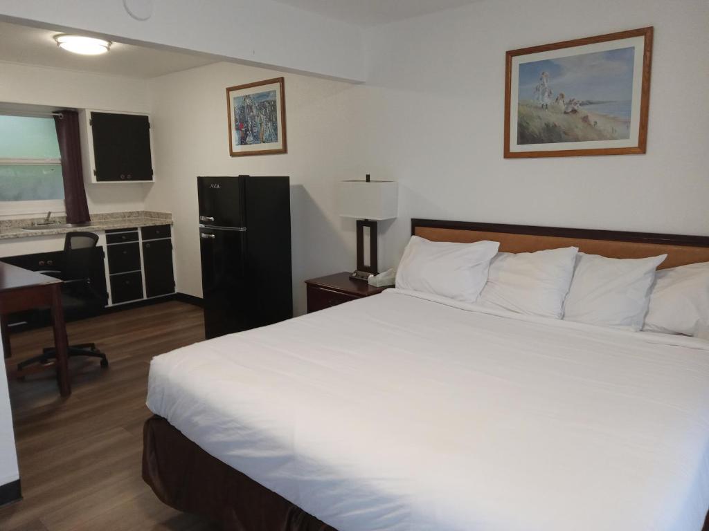 布鲁金斯蓝色海岸套房酒店的一间带白色大床的卧室和一间厨房