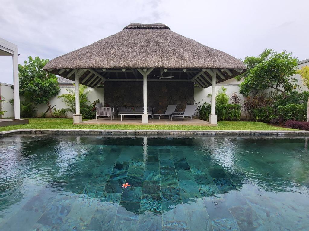 格兰贝伊Villa de Luxe à Grand Baie avec piscine V12的一个带茅草凉亭的大型游泳池